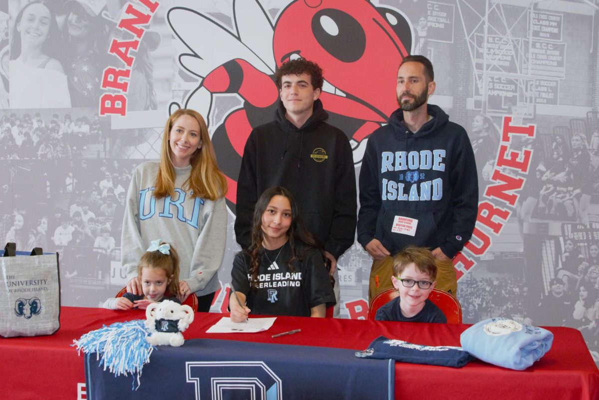 Madison Polce, center, pauses with her family and friends while signing to continue cheerleading next year at the University of Rhode Island.